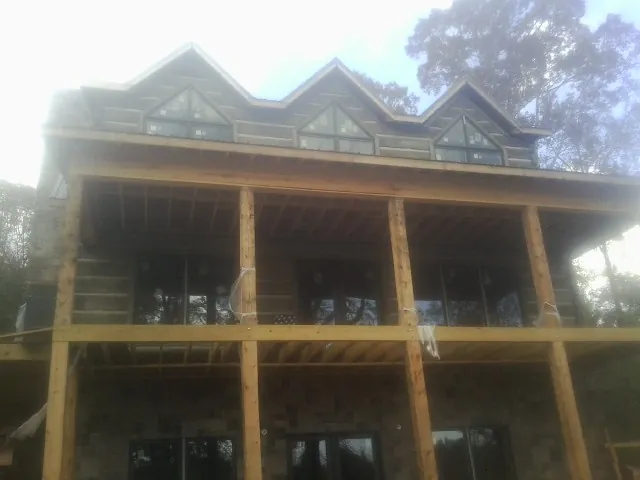 Dormers and porch framing on a large log home under construction — Roof Coating work by our crew in Osyka