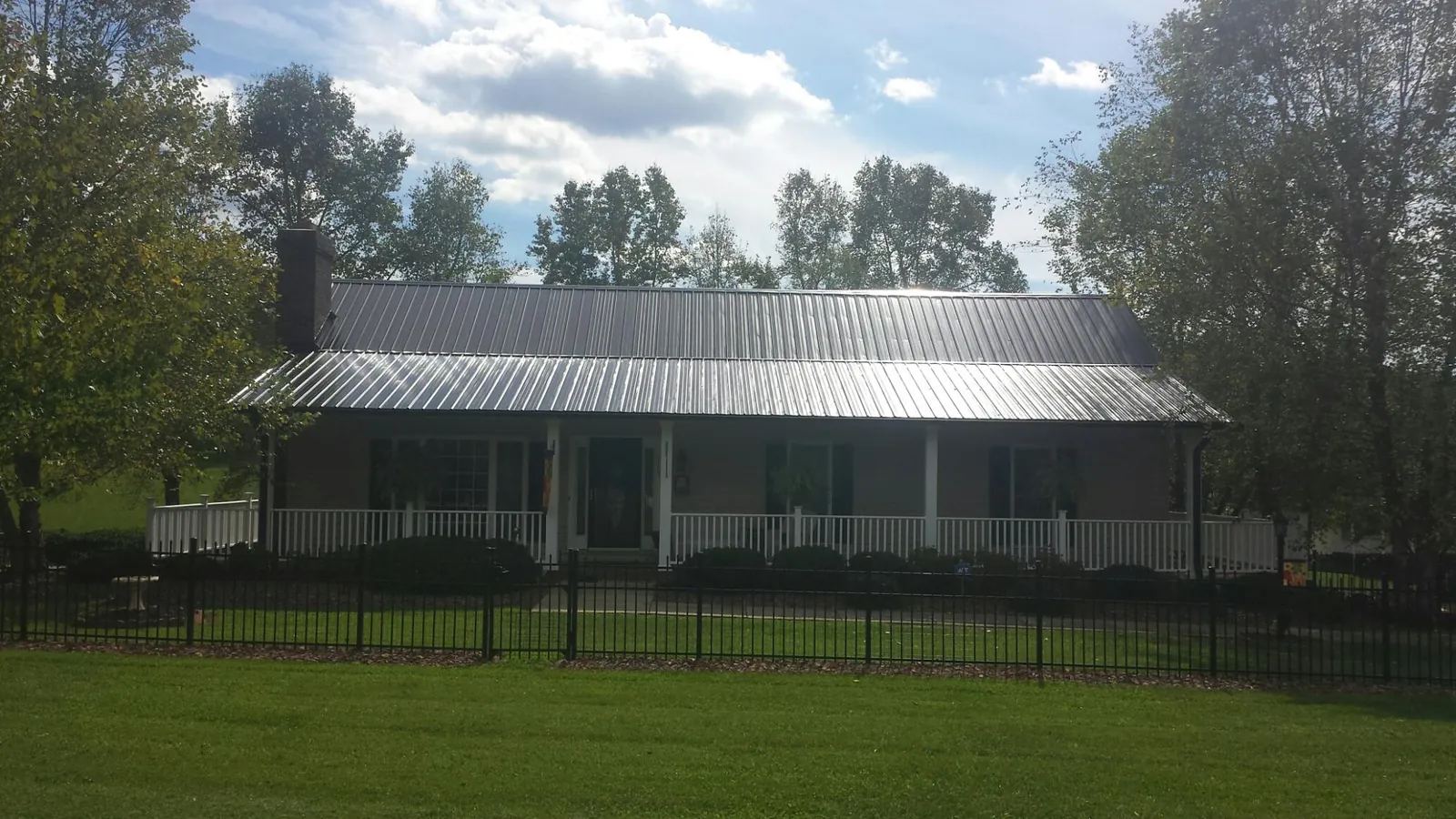 Gray metal roof on a brick ranch with a full width front porch — Gutter Guard Installation work by our crew in Osyka