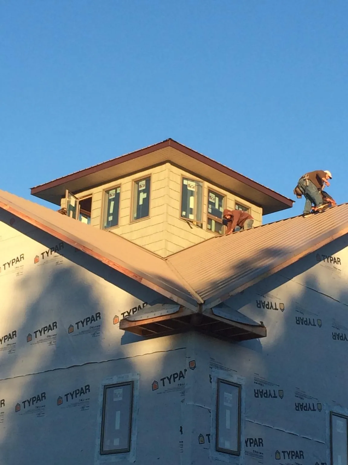 Roofers working around a rooftop cupola on a new metal roof at sunset — Roof Waterproofing in Osyka by Roofing Brothers